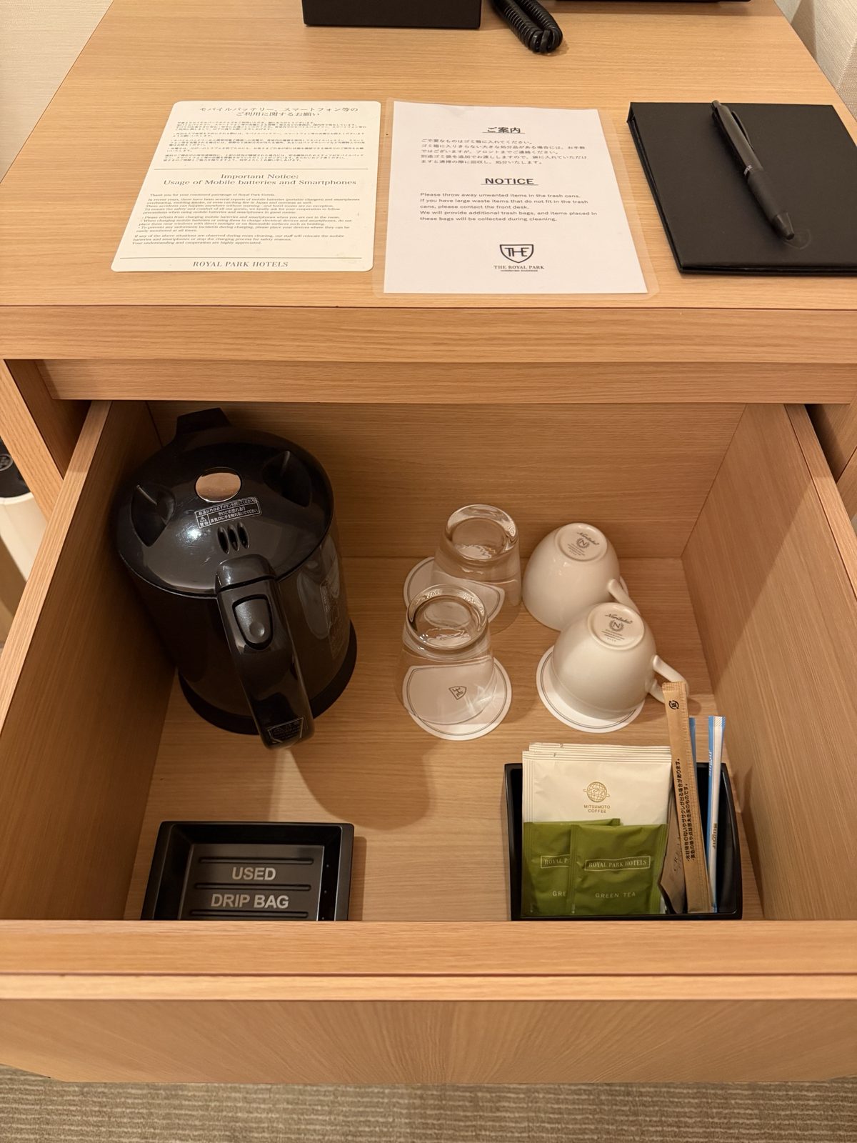 デスクの引き出しに収納された電気ケトル、ノリタケのカップ、ドリップコーヒーと緑茶