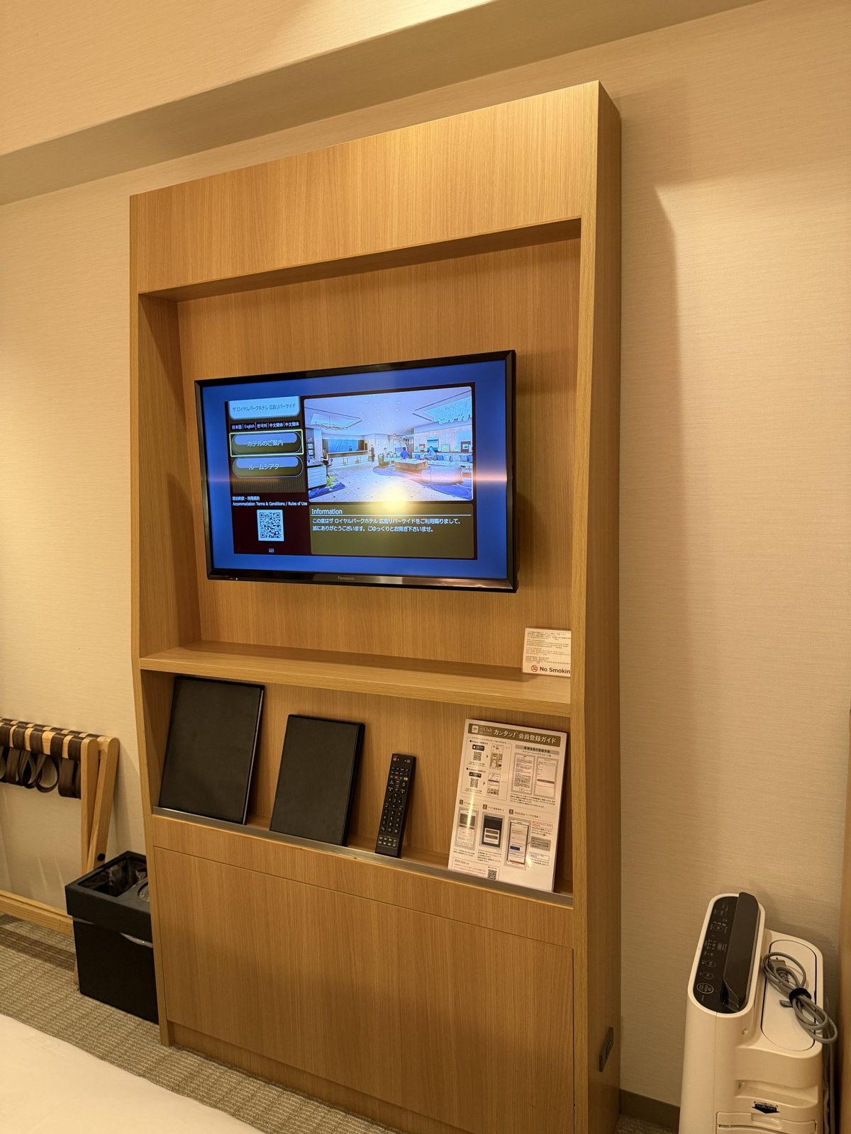 木製の壁面収納に組み込まれたテレビ。下段に館内案内とリモコン