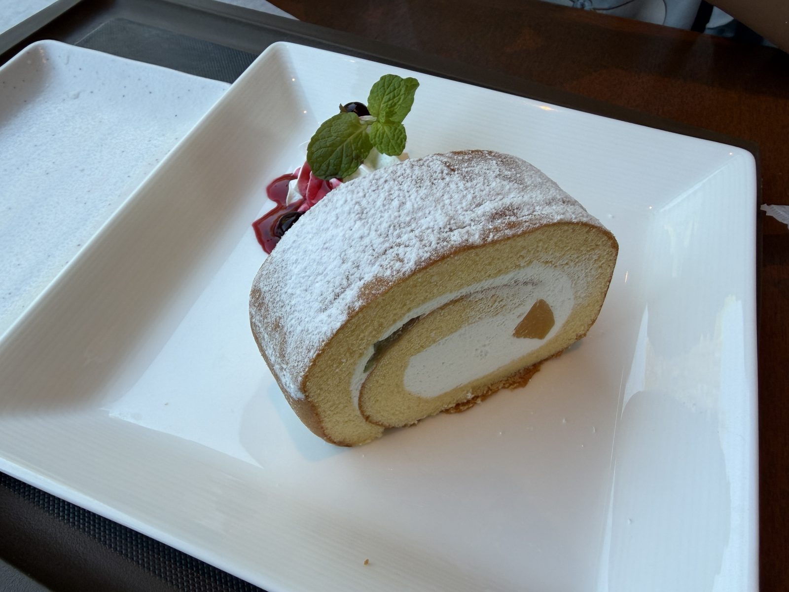 cafe Art（東京都美術館）のフルーツロールケーキ。粉糖をかけた生地にベリーソースとミントを添えた一皿